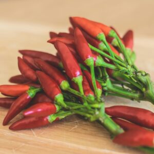 Close-up of vibrant red chili peppers arranged on a wooden cutting board, perfect for spicy dishes.
