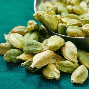 A detailed close-up of fresh organic green cardamom pods on a textured surface.